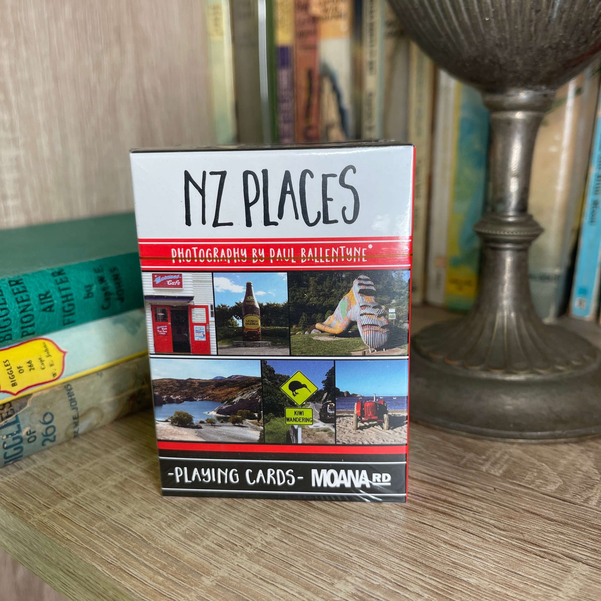 Pack of playing cards featuring NZ places sitting on a book shelf.