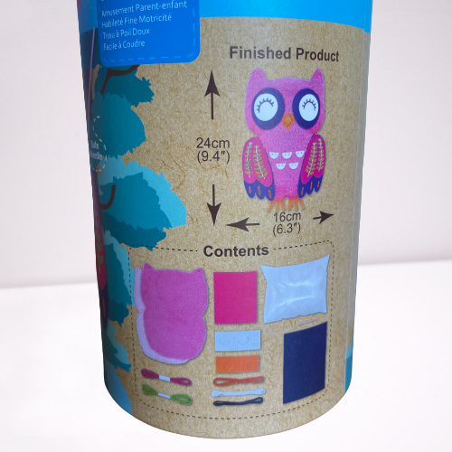 Close up of the contents in a Childrens owl sewing kit in a cardboard tube.