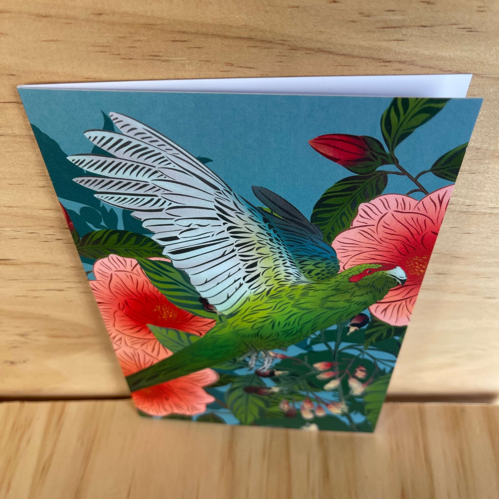 Greeting card by designer Flox featuring a Kakariki bird and Camellia flowers.