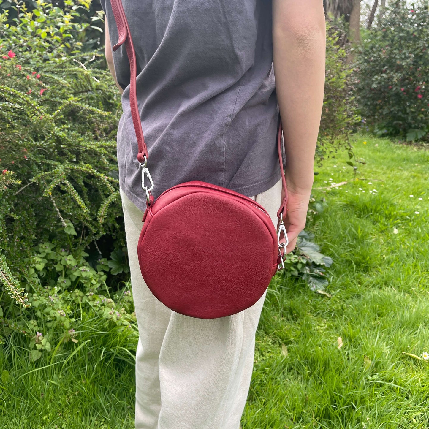 Red circular handbag with front pocket.