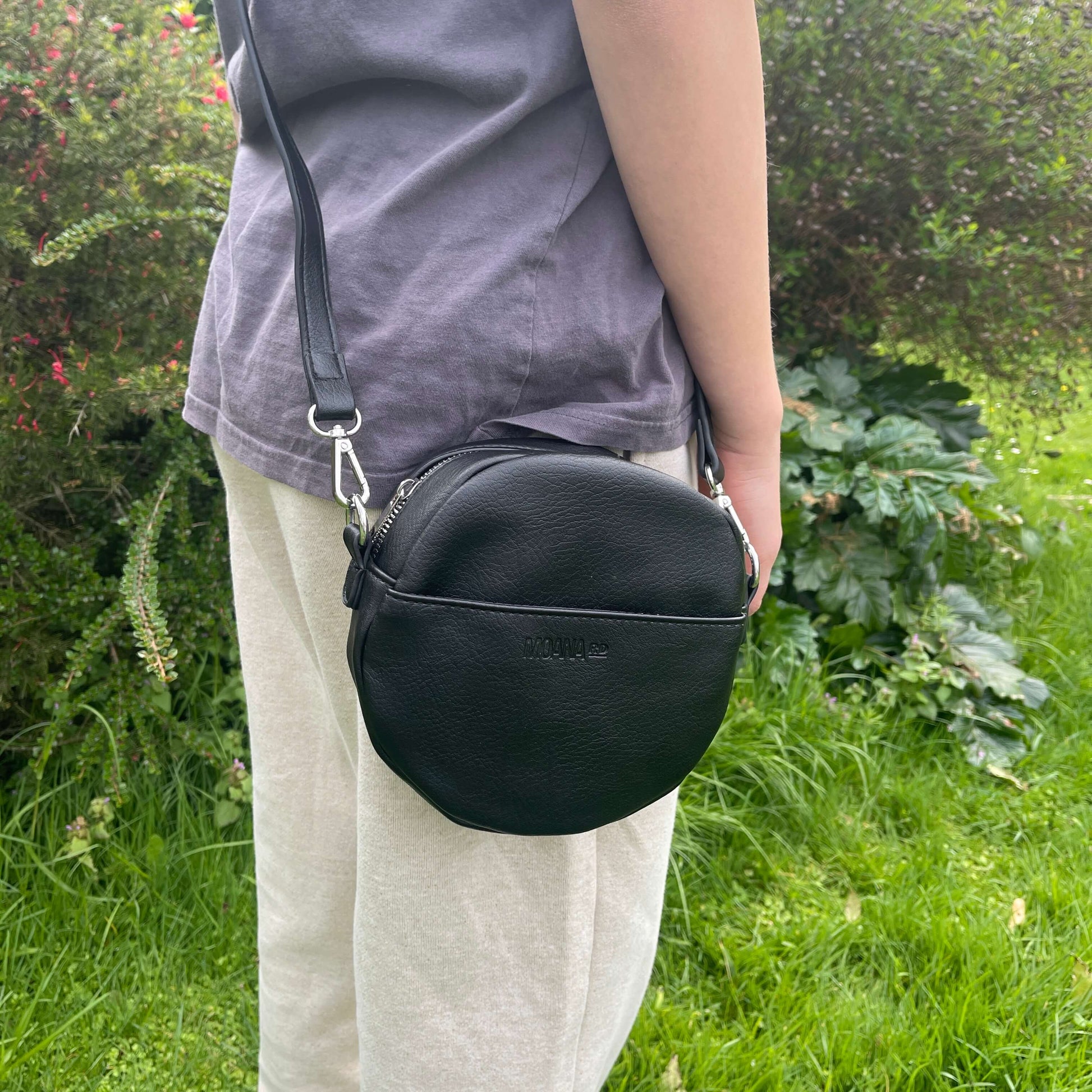 Black circular shoulder bag with front pocket.
