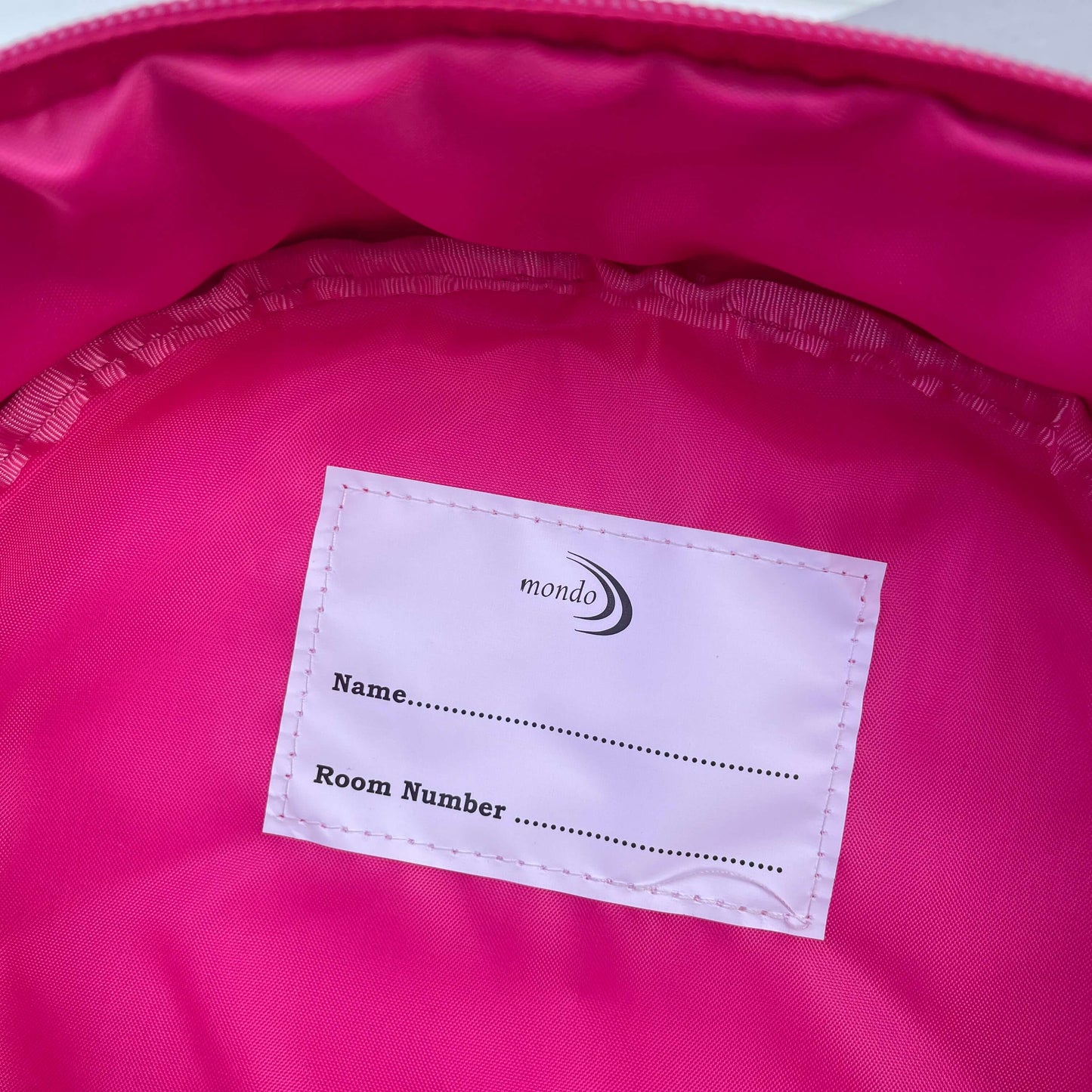 Inside a bright pink backpack showing name label.