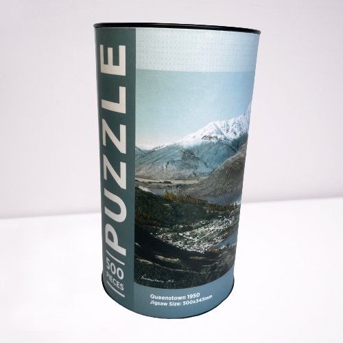 Cardboard tube with a jigsaw puzzle inside featuring artwork of the Queenstown.