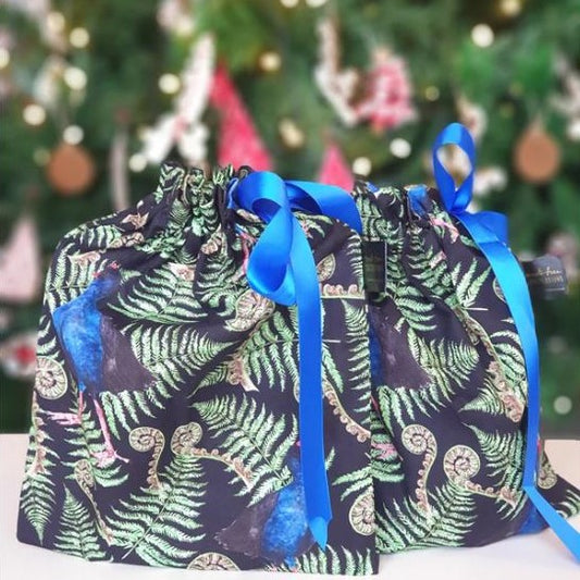 Reusable christmas gift bags with a fern and pukeko print and blue ribbon.