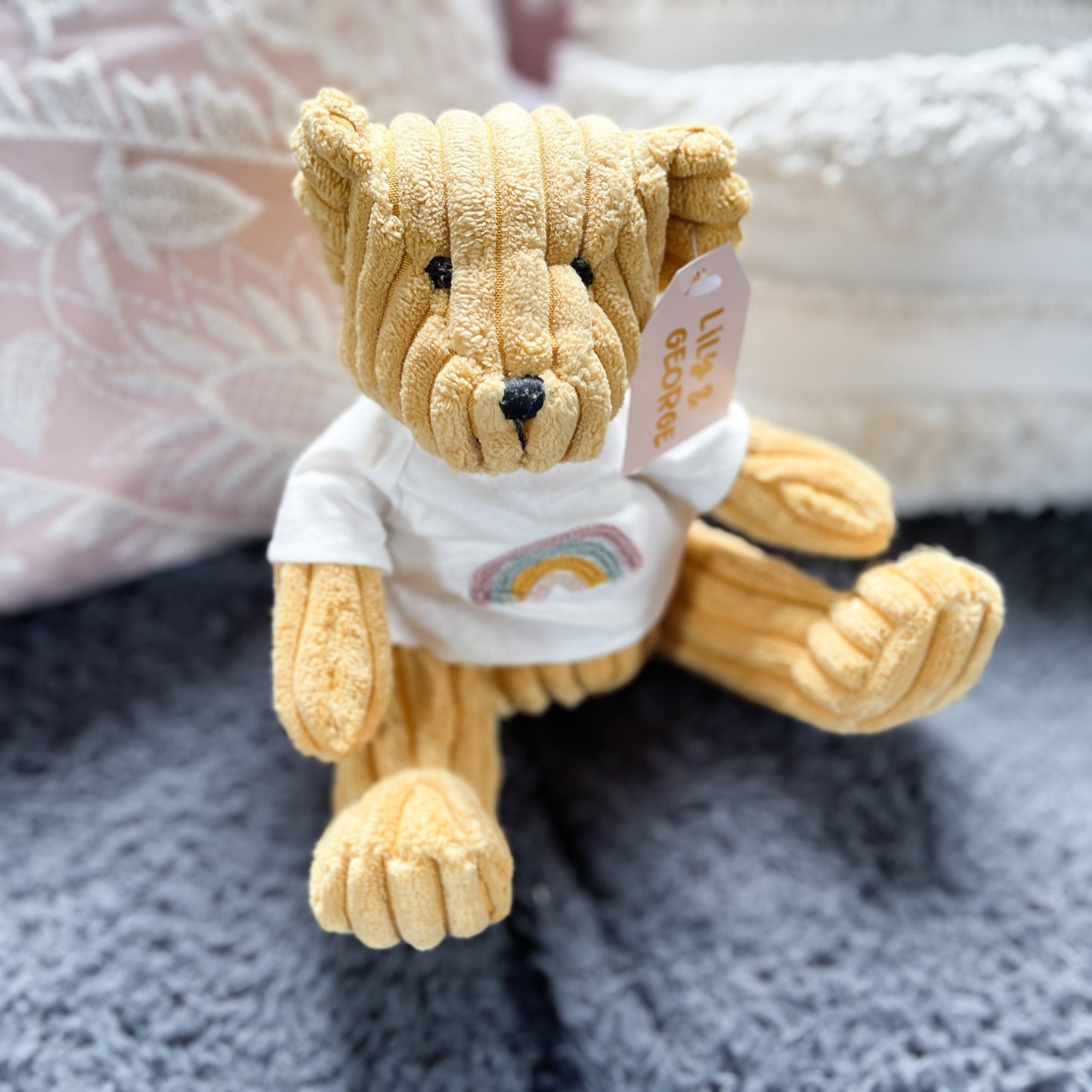 Saffron coloured teddy bear with a rainbow on his t.shirt.