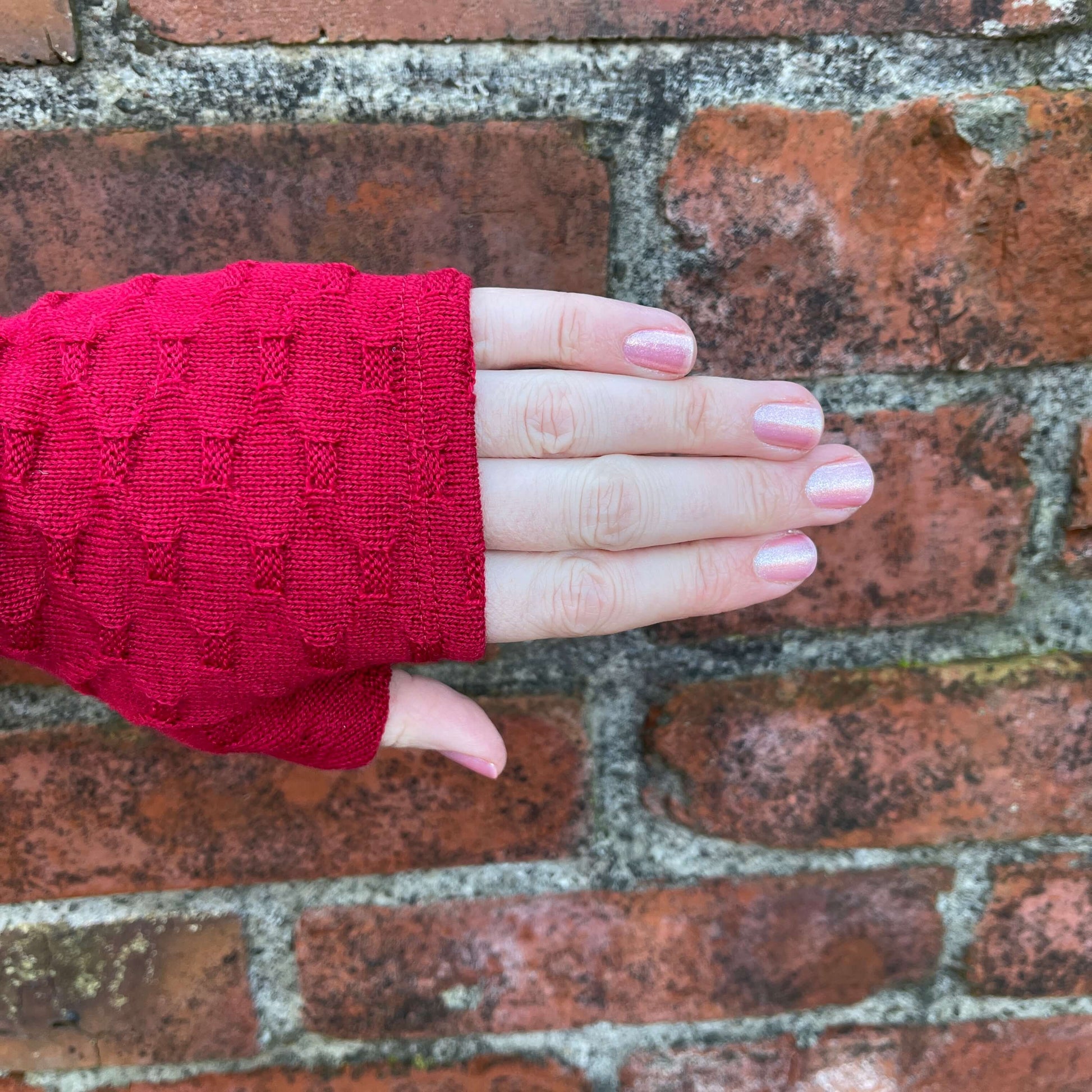 Fingerless merino gloves in red textured knit.