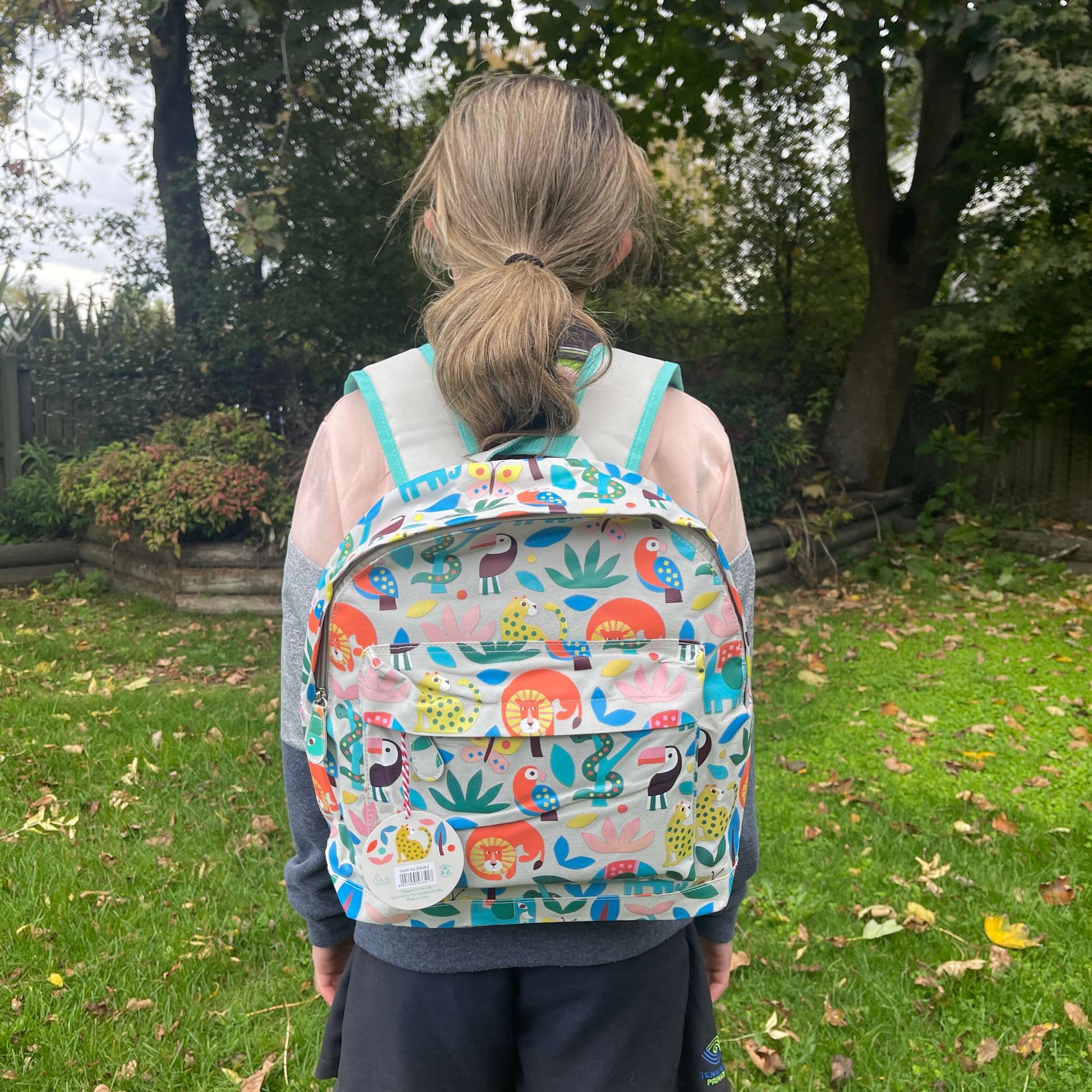 Girl wearing a backpack with bright jungle animals printed on it.