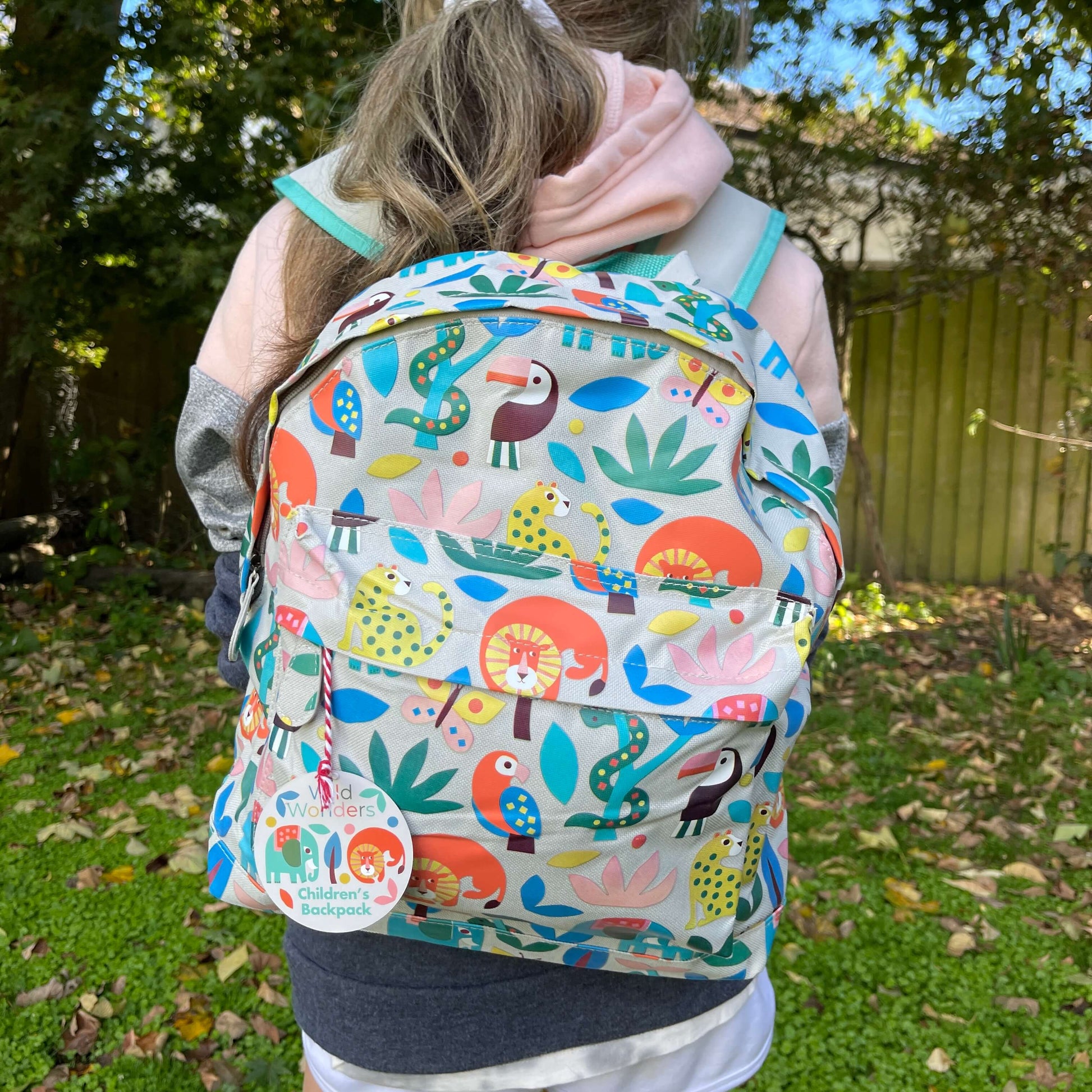 Girl wearing a backpack with bright jungle animals printed on it.