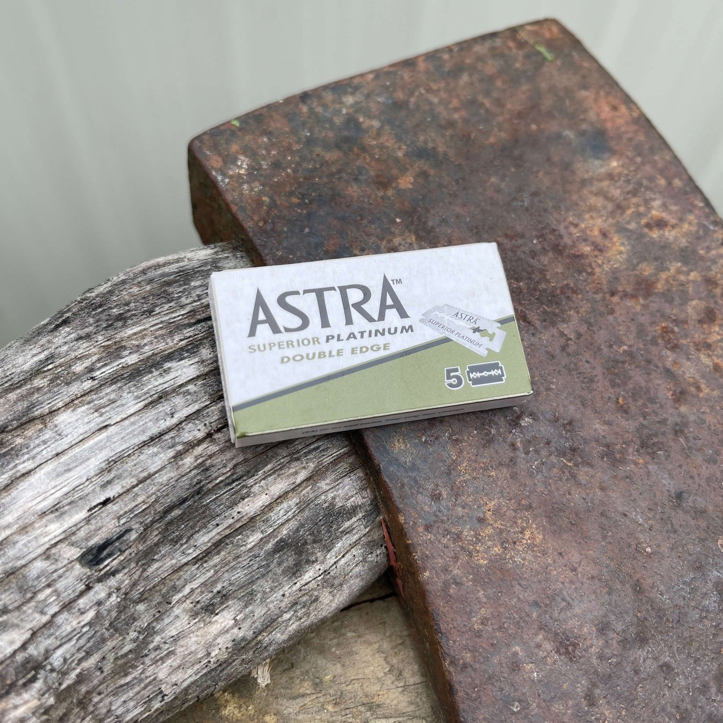 Small box of 5 razor blades for a safety razor sitting on an axe blade.