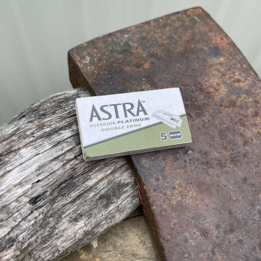 Small box of 5 razor blades for a safety razor sitting on an axe blade.