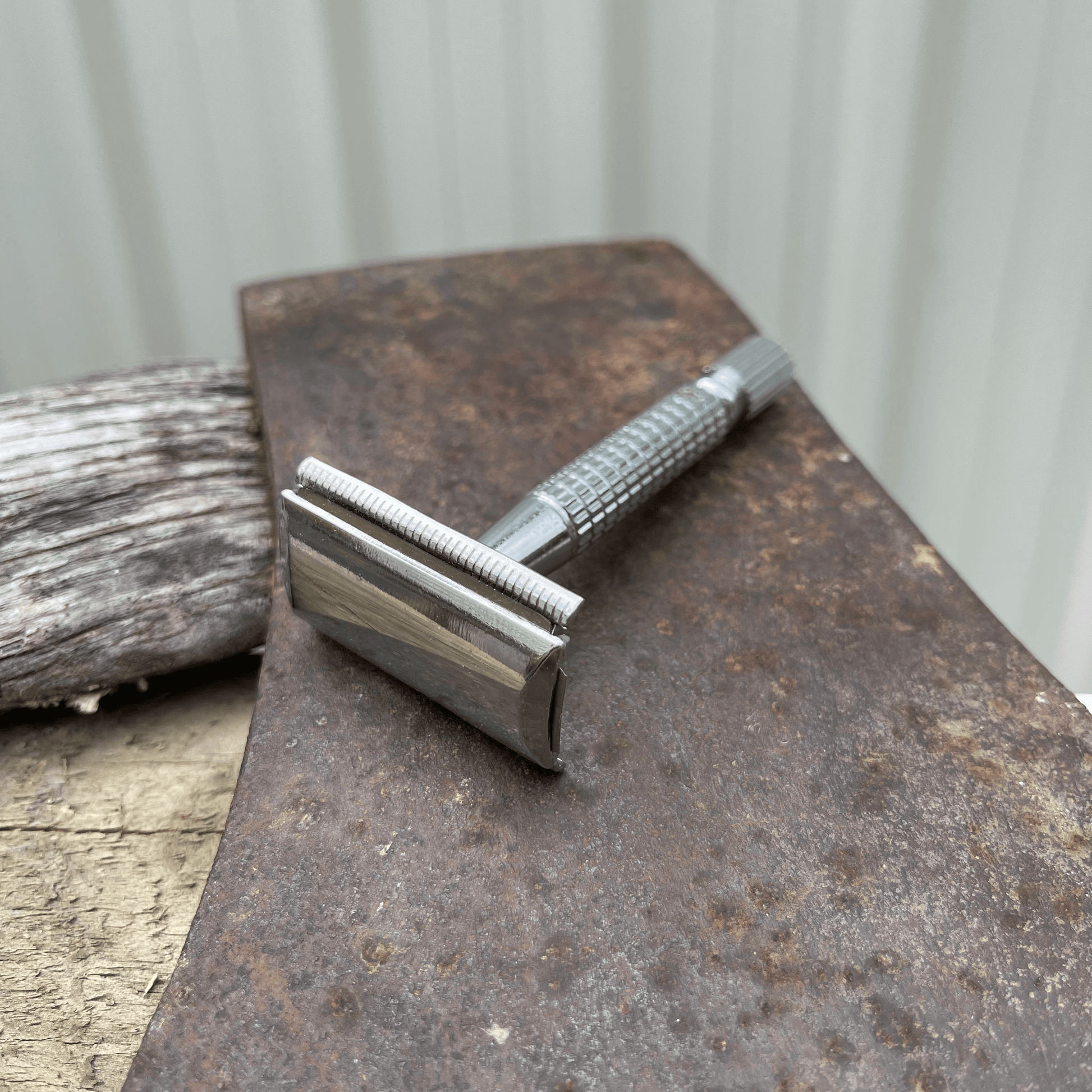 Metal safety razor sitting on the blade of an axe.