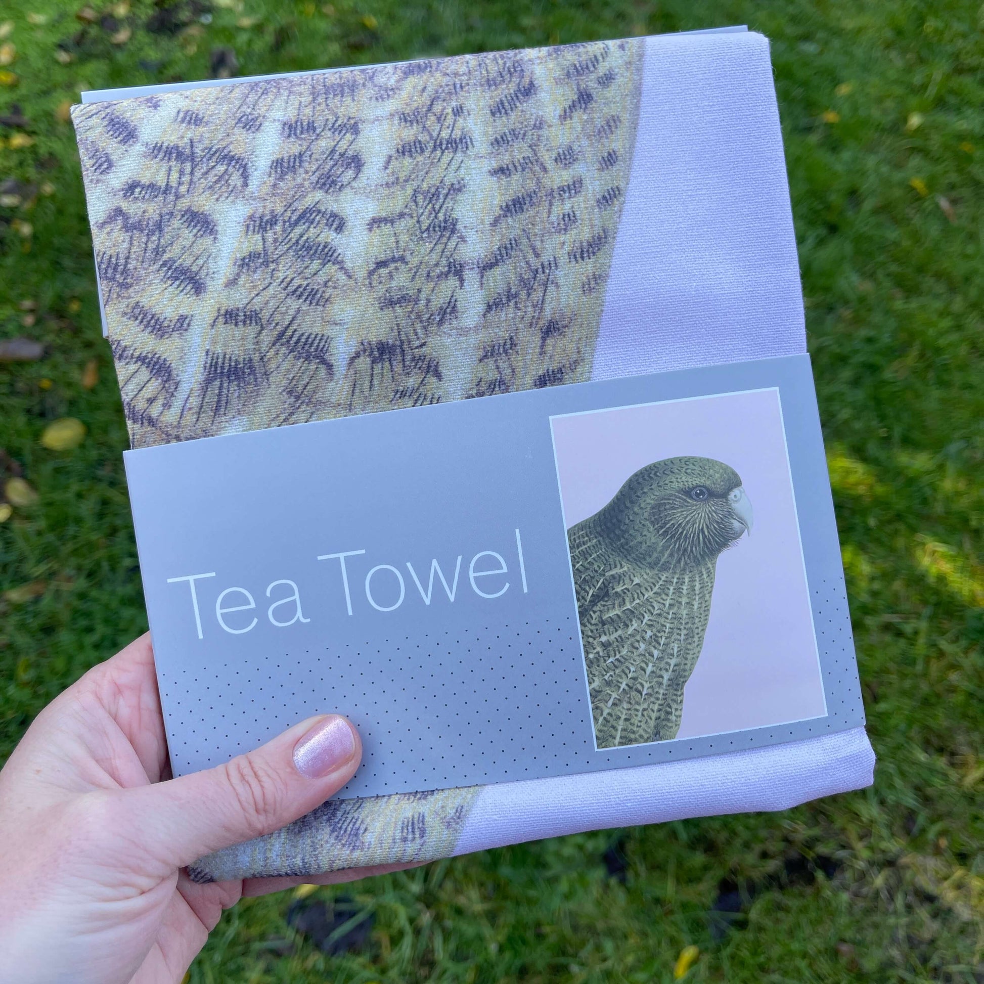 Pale pink tea towel with a Kakapo bird on it.