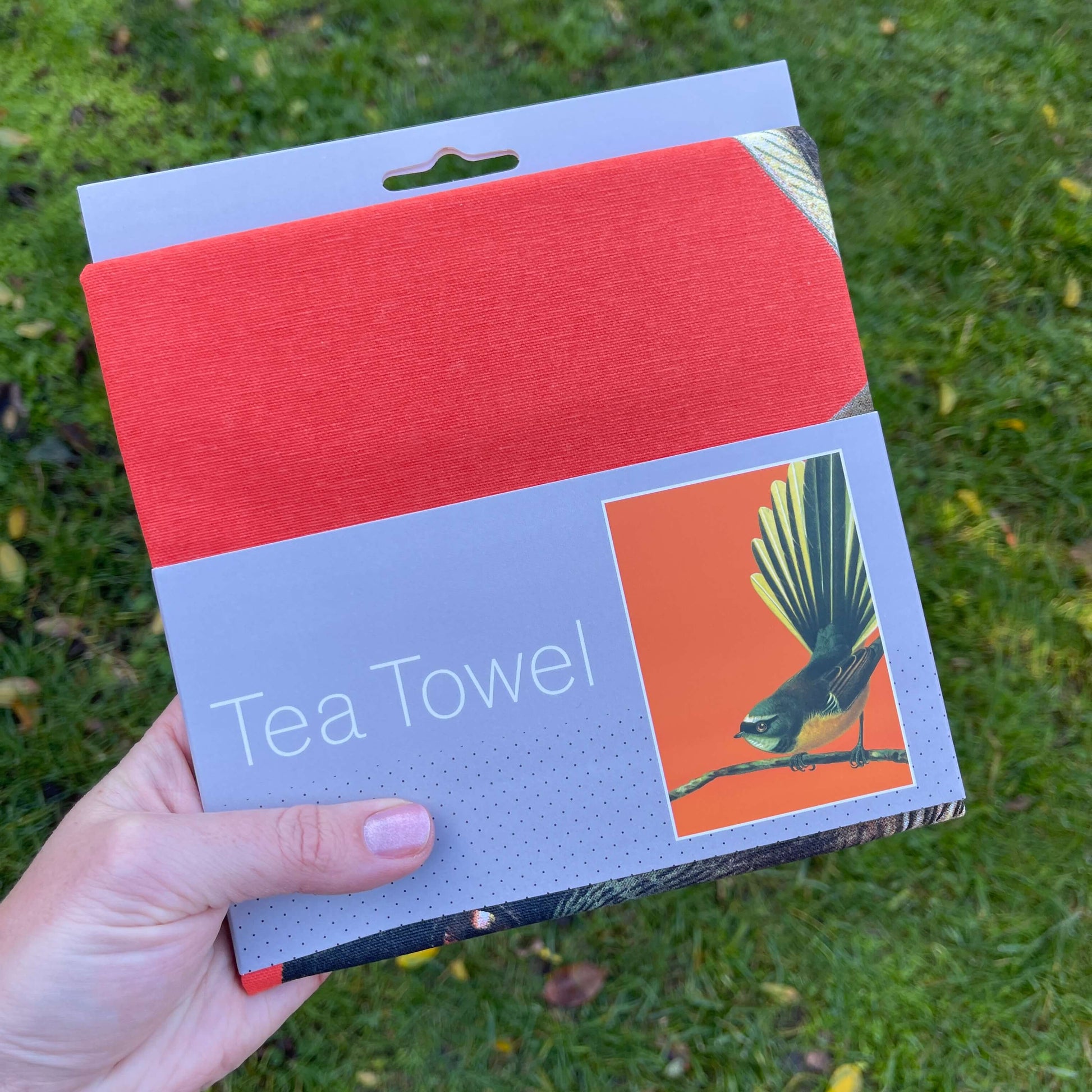 Bright orange Tea towel with a fantail on it.