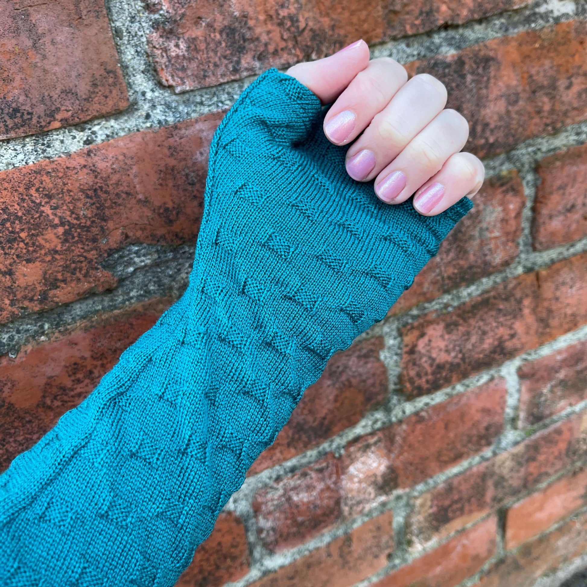 Fingerless merino gloves in teal textured knit.