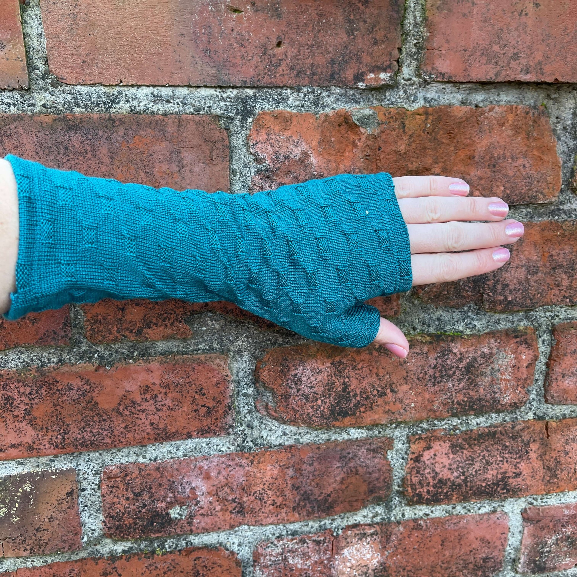 Fingerless merino gloves in teal textured knit.