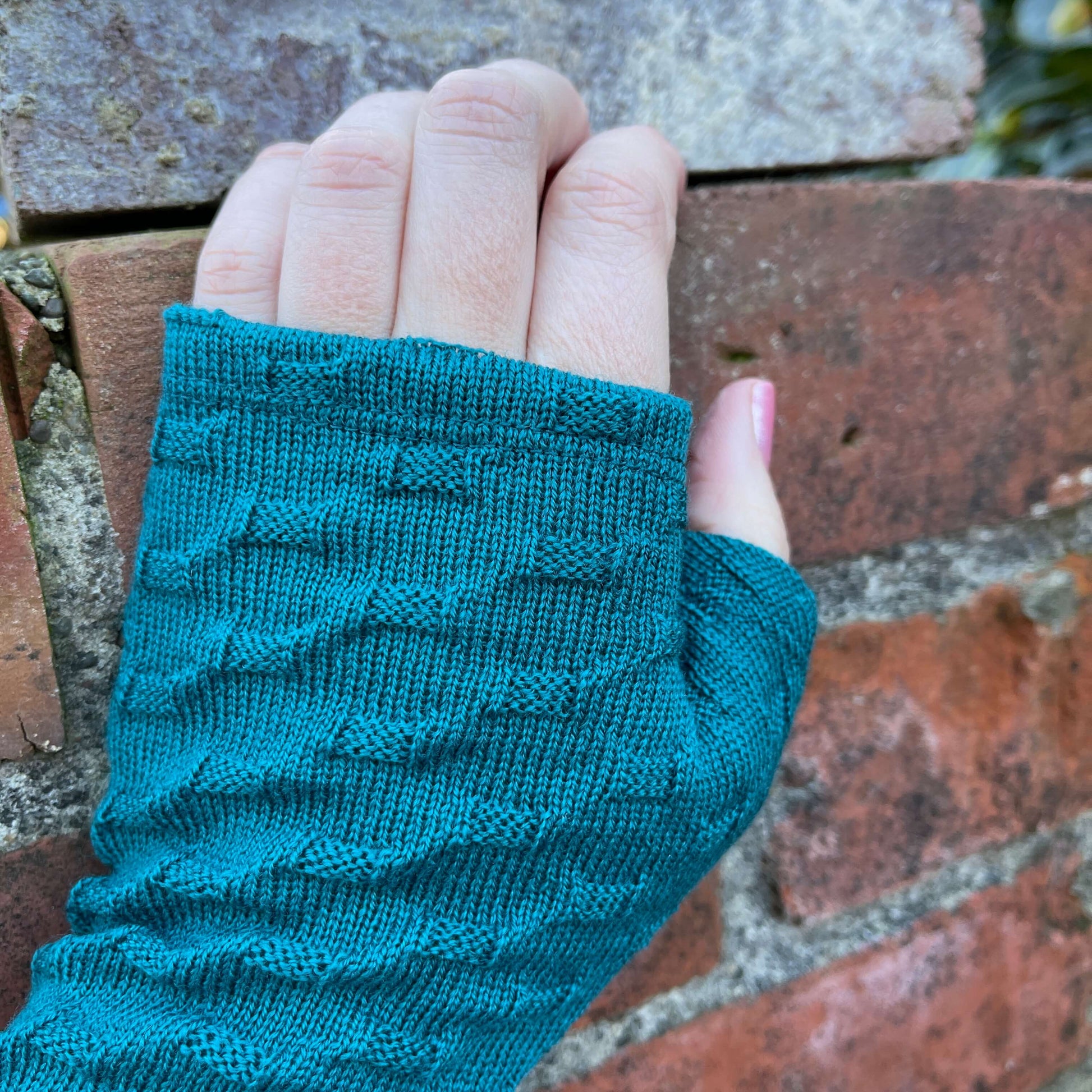 Fingerless merino gloves in teal textured knit.