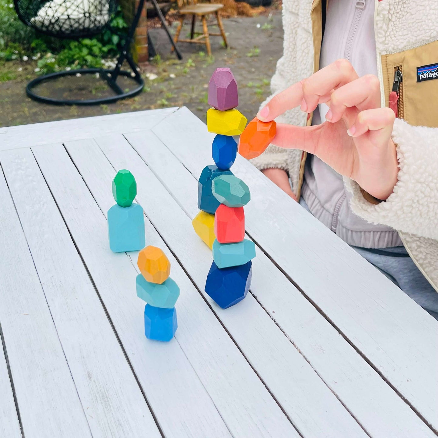 Child playing with colourful wooden balancing gems.