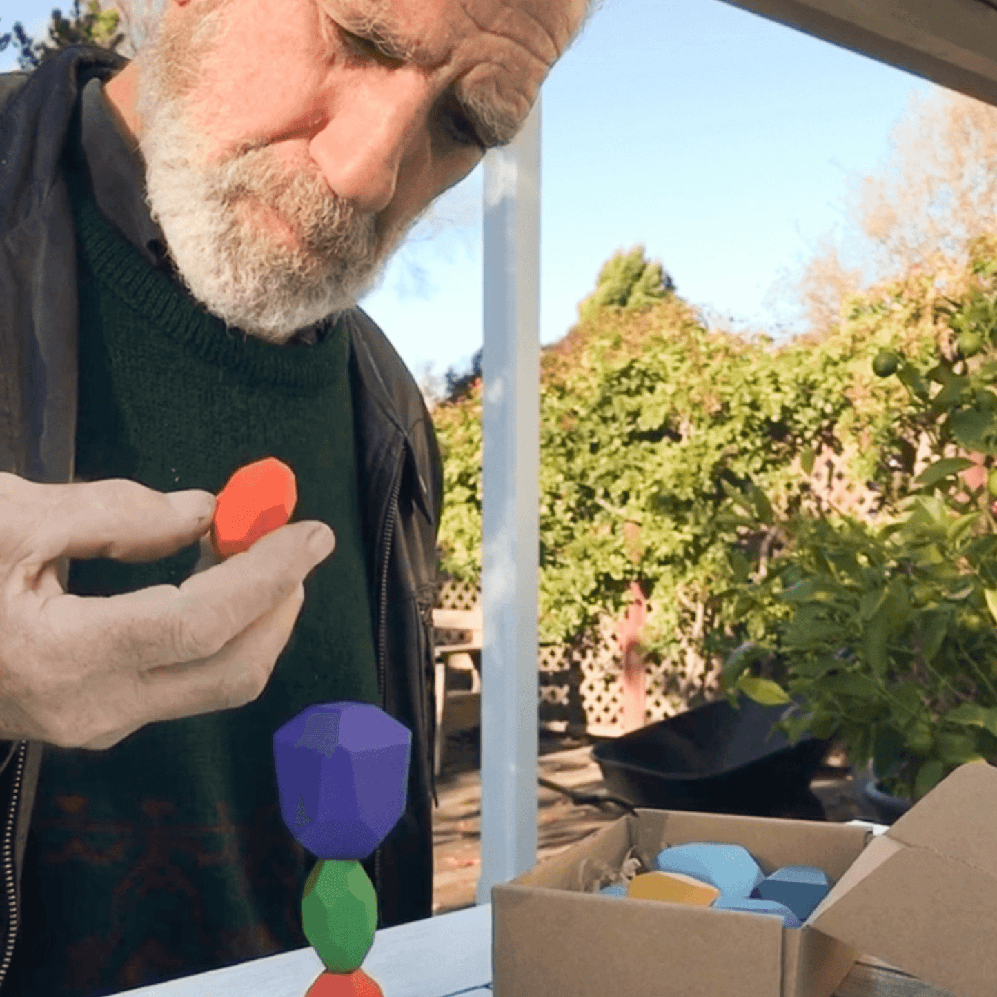 Man playing with colourful wooden balancing gems.
