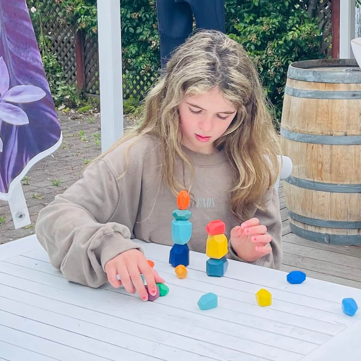 Child playing with colourful wooden balancing gems.
