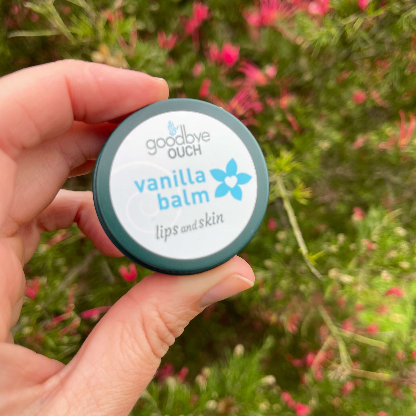 Persons hand holding a small tin of Vanilla Balm.