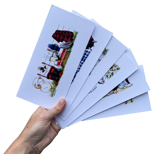 Persons hand holding 6 greeting cards with kiwiana artwork.