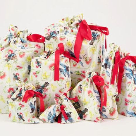 Reusable gift bags with a kiwiana flora and fauna pattern and red ribbon.