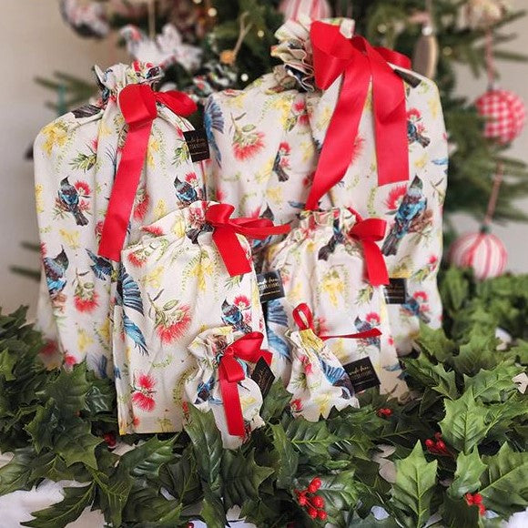 Reusable gift bags with a kiwiana flora and fauna pattern and red ribbon.