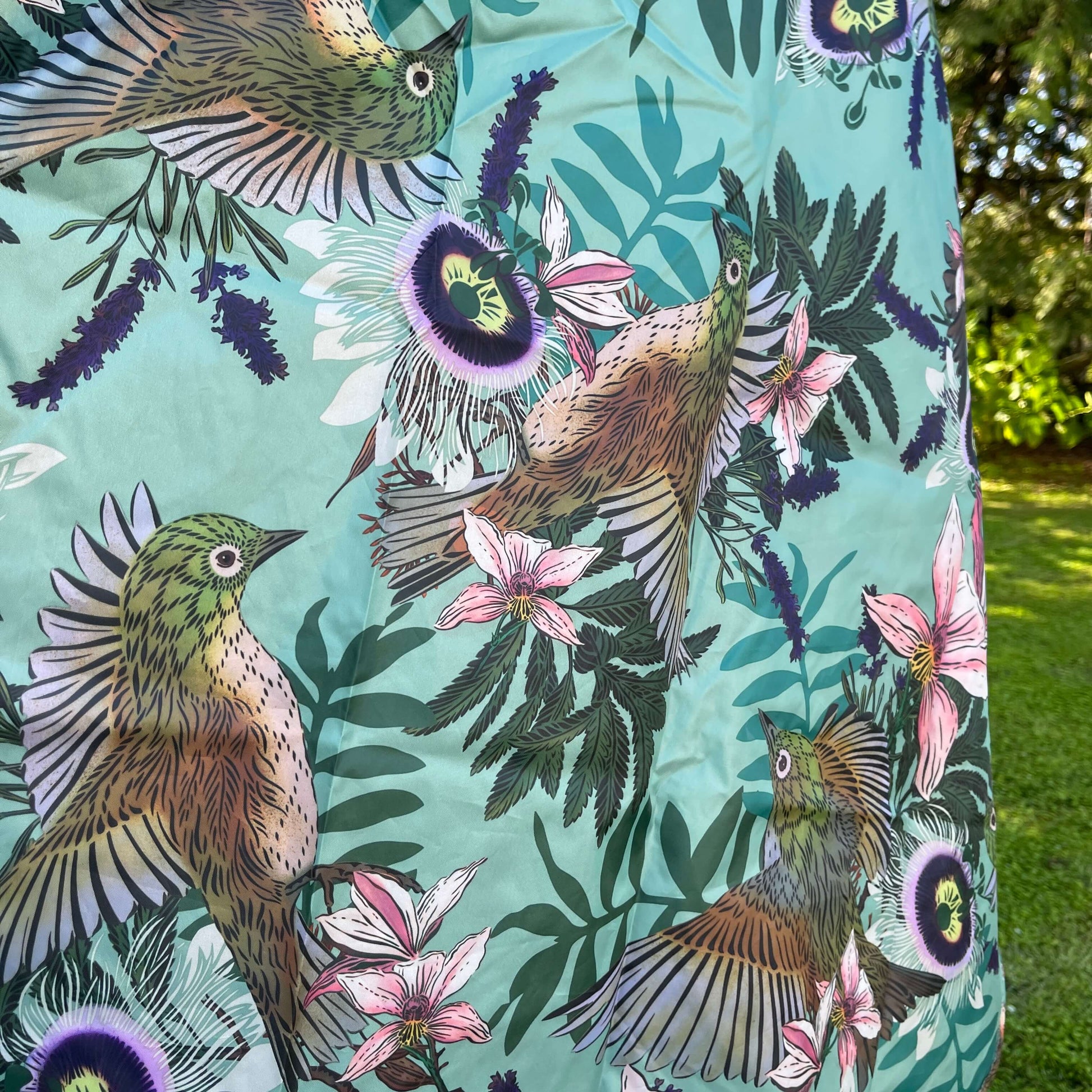 Close up of a rain poncho showing the Waxeye bird and floral print.
