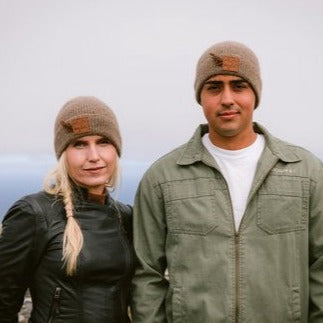 Couple wearing brown knit beanie hat with a weka feather.