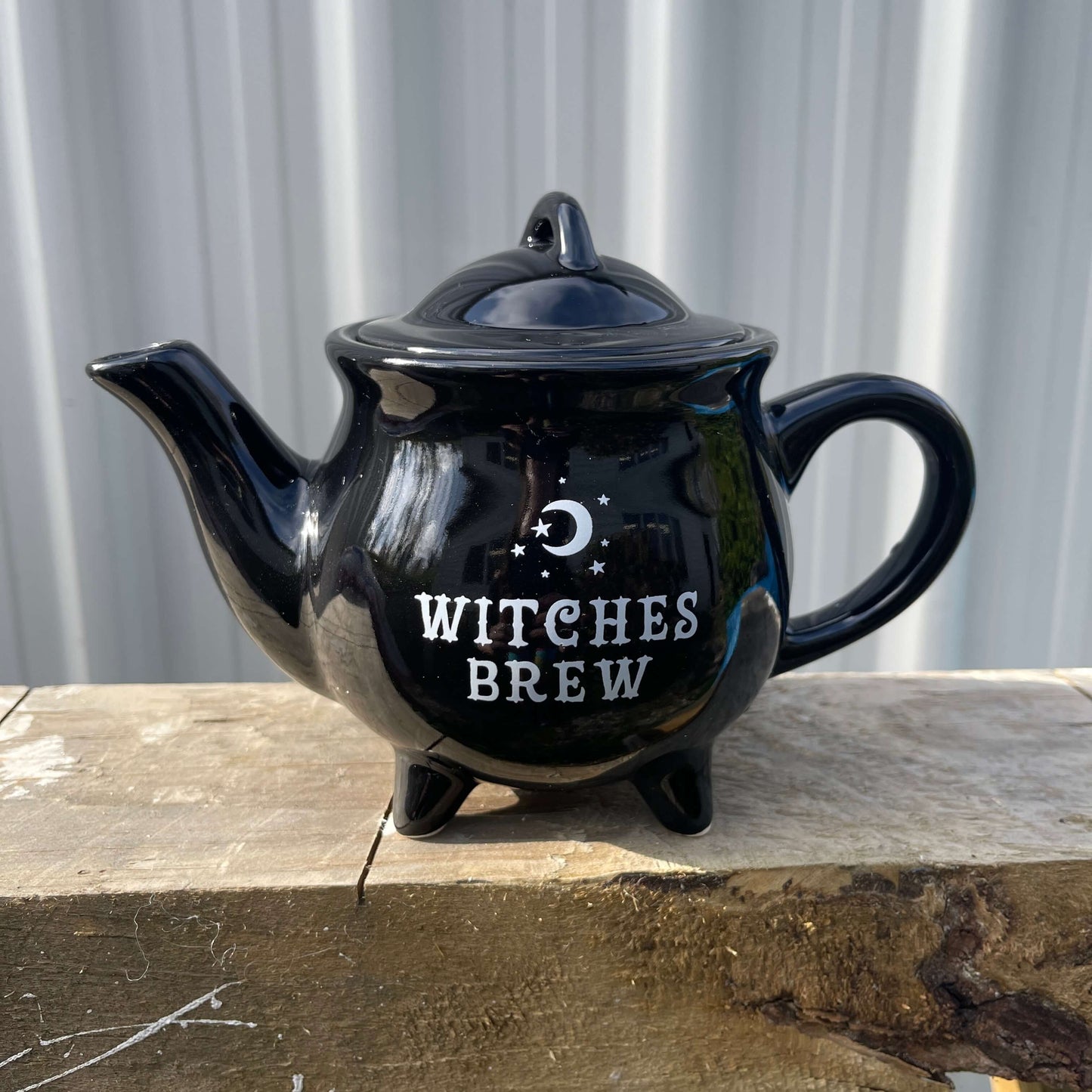 Black teapot with Witches Brew written on it in white.