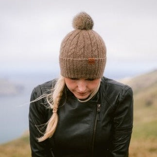 Lady wearing brown knit beanies with pompoms.