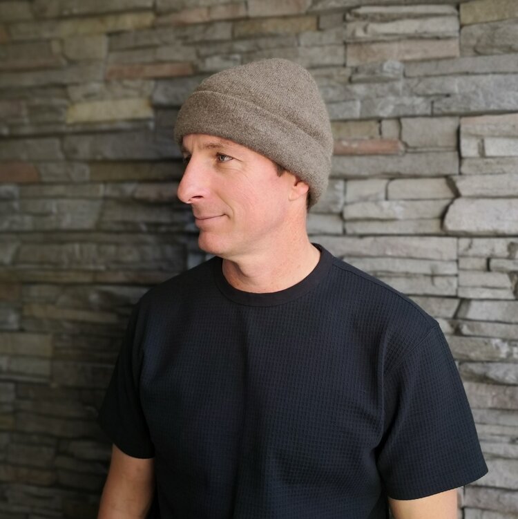 Man wearing a Wyld Ultimate beanie against a stone wall.