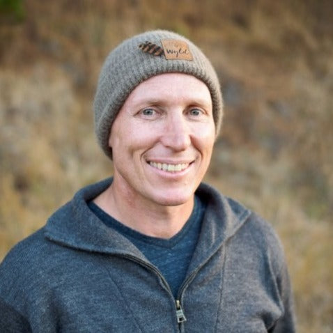 Portrait of a man wearing a Wyld  Weka knit beanie with a Weka feather.