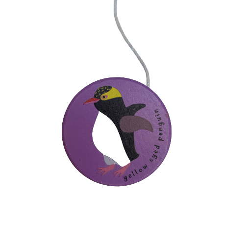 Purple wooden yoyo with a Yellow Eyed Penguin painted on it.