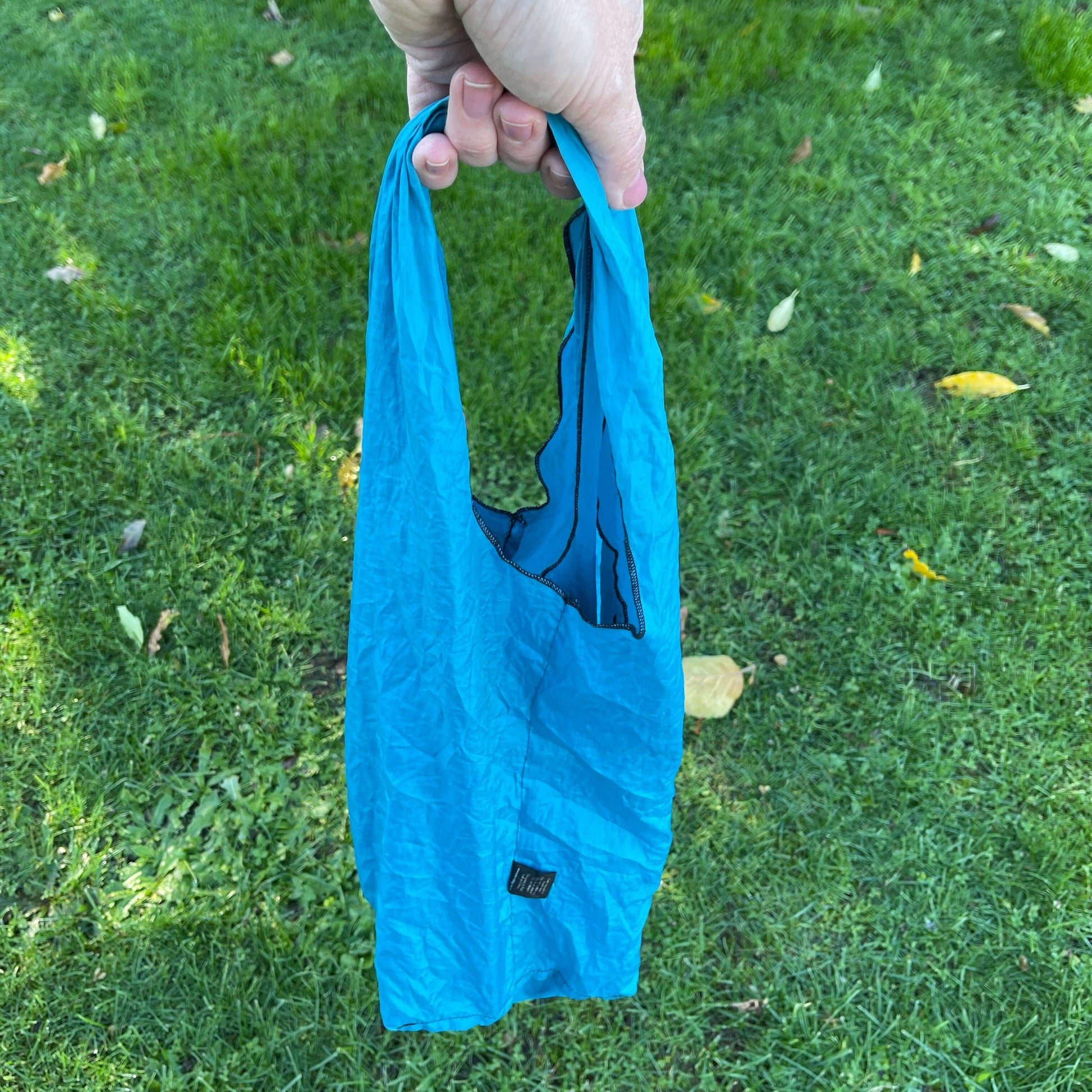 Blue tote bag being held in hand.
