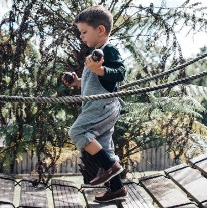 Child wearing crew length socks on a balancing bridge in a playground.